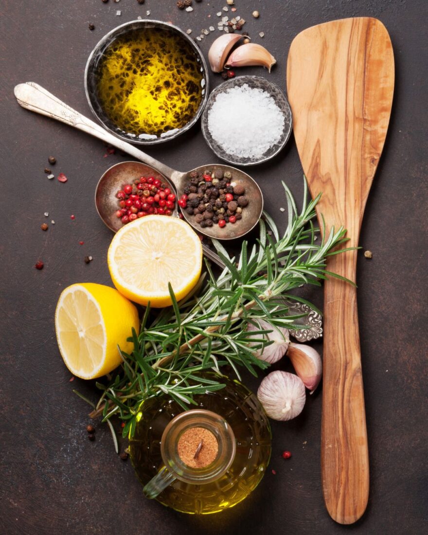 Olivenöl & Gewürze im Winter: 4 wärmende Kombis mit Charakter 2 Winterliche Gewürze mit Olivenöl, Rosmarin, Knoblauch, Zitrone und grobem Salz auf dunklem Hintergrund