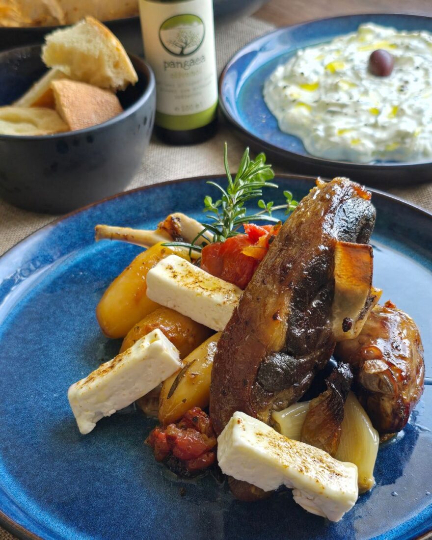 Nahaufnahme von Lammfleisch, Feta, Kartoffeln und Kräutern – im Hintergrund Pangaea Olivenöl