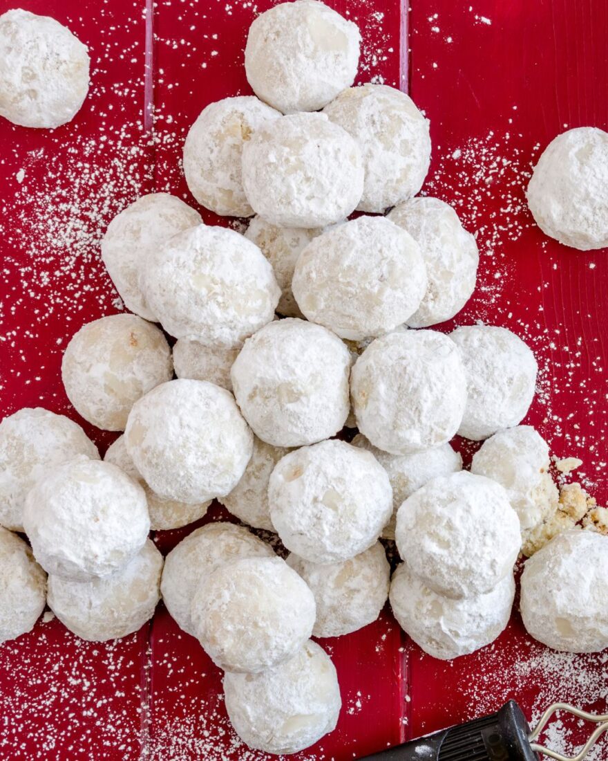 Kourabiedes Rezept – Griechische Butter-Mandeln-Kekse 2 Griechische Kourabiedes – zart mürbe Butterkekse mit Puderzucker auf rotem Untergrund