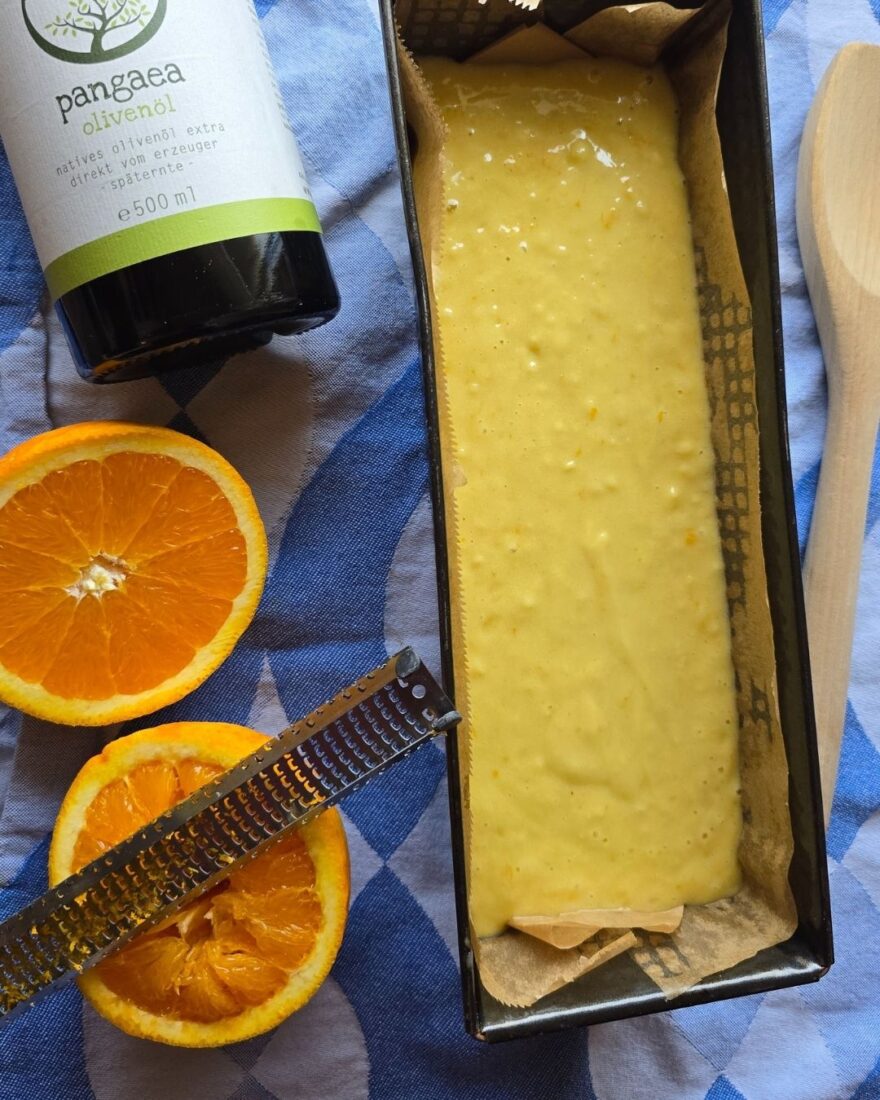 Olivenölkuchen Rezept – saftig, einfach & mit Joghurt 5 Olivenölkuchenteig in Backform, daneben Orange und Reibe