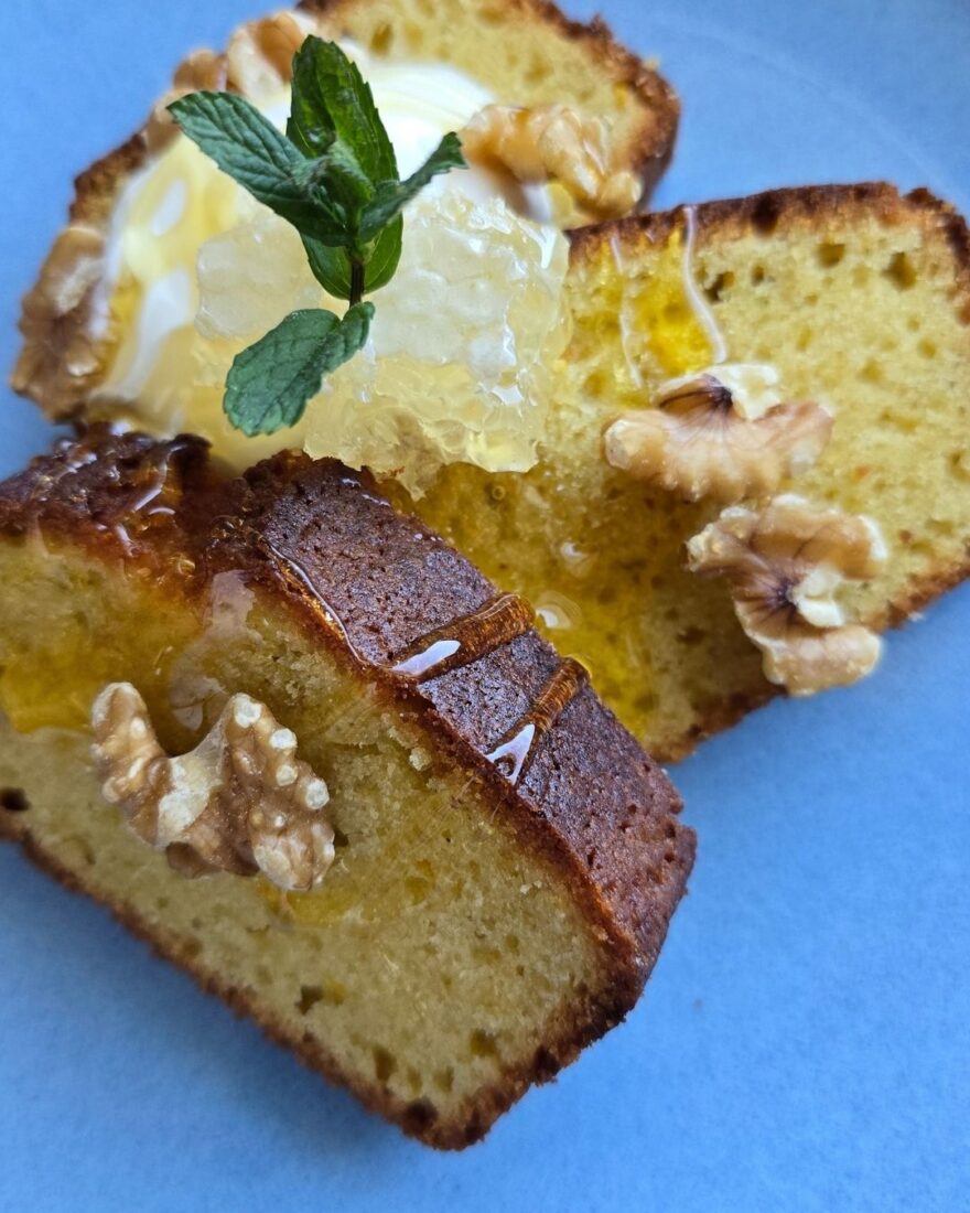 Olivenölkuchen Rezept – saftig, einfach & mit Joghurt 2 Saftiger Olivenölkuchen mit Honig, Walnüssen und Minze auf blauem Teller