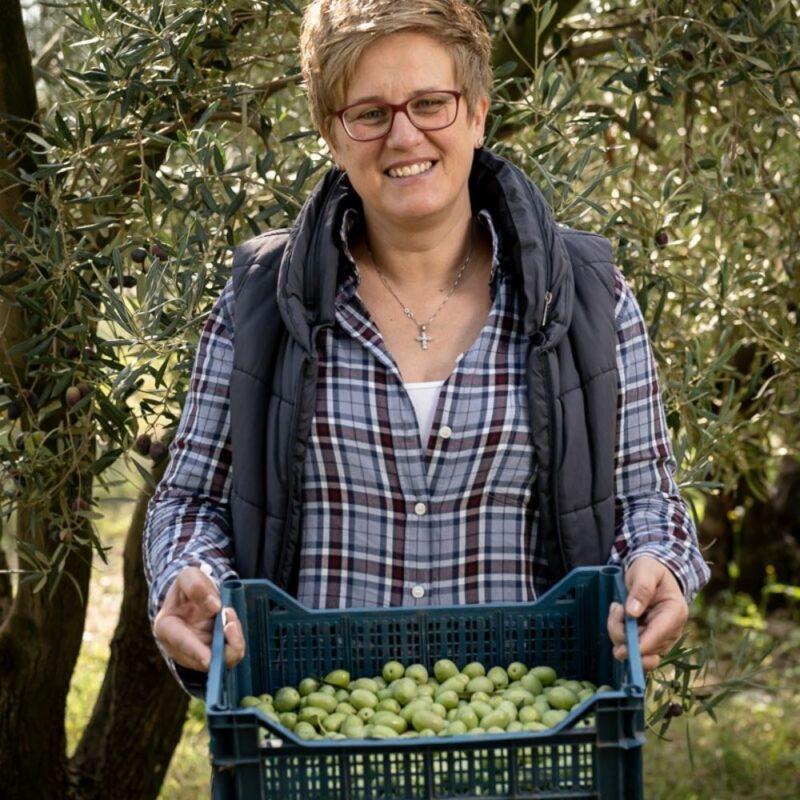 Julia Lakirdakis-Stefanou mit einer Kiste frisch geernteten, grünen Oliven
