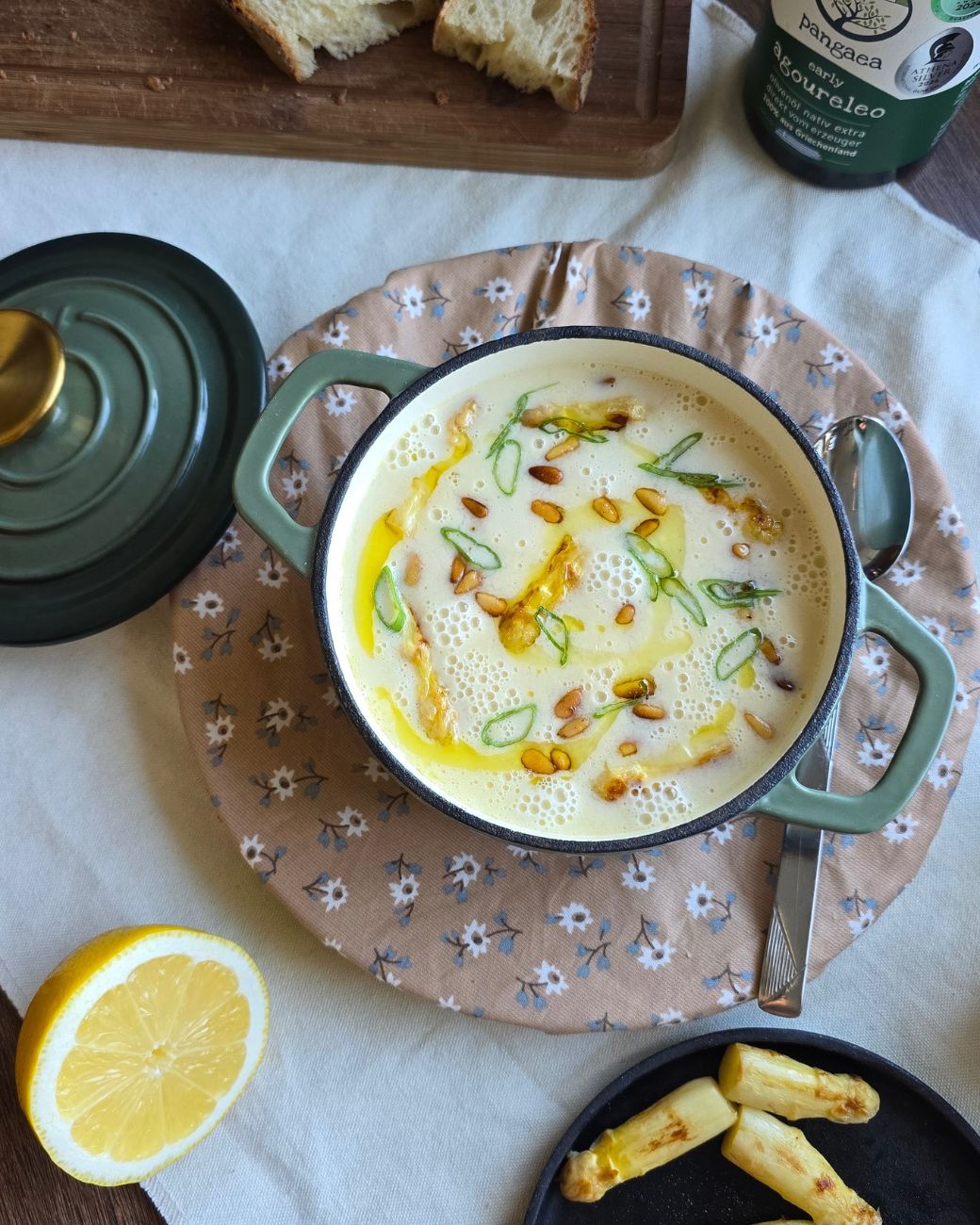 Spargelcremesuppe mit Zitronenscheibe, Löffel und Pangaea Olivenöl serviert