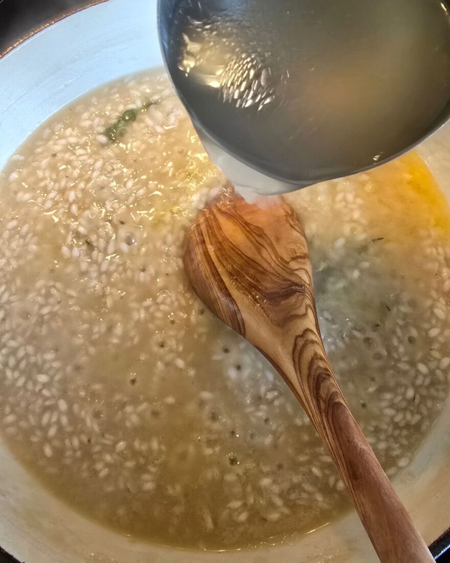 Fond wird mit Kelle ins Risotto gegeben